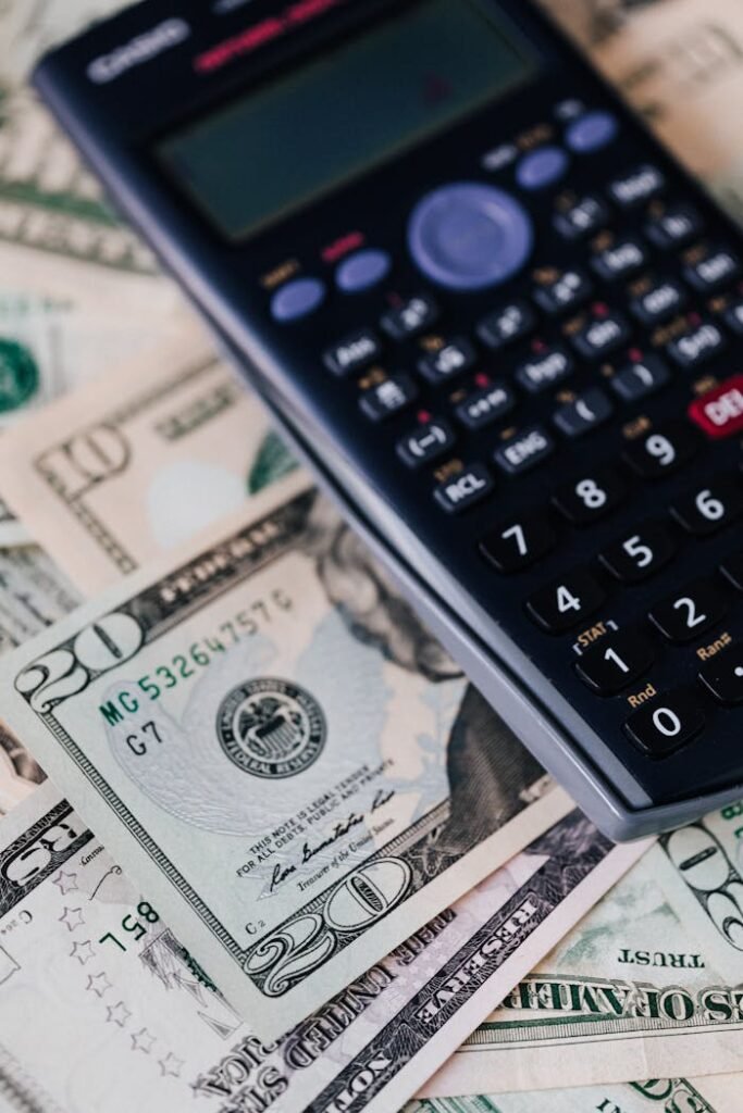 From above of calculator placed on paper banknotes of American dollars on table